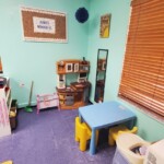 Debary Sonshine Academy classroom play corner with a toy kitchen and a dining table with chairs.