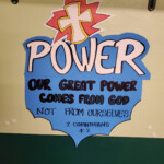 A hand-drawn sign 'Power: Our Great Power Comes From God Not From Ourselves'.